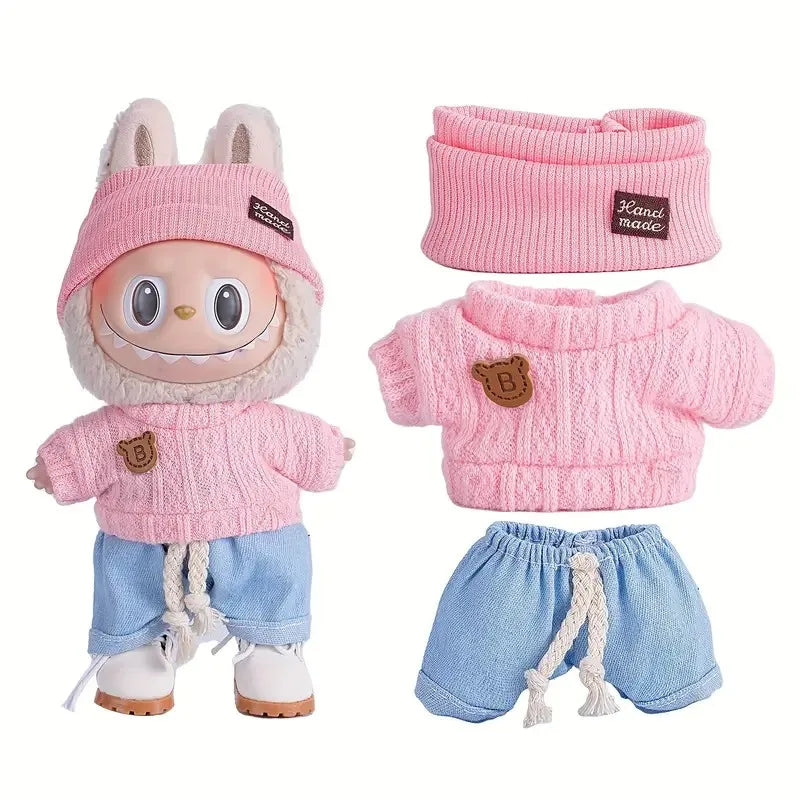 A set of pink and blue knitted outfits for a doll figure including a sweater and shorts.