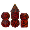 A set of seven faceted, translucent red resin polyhedral dice with black crack patterns.