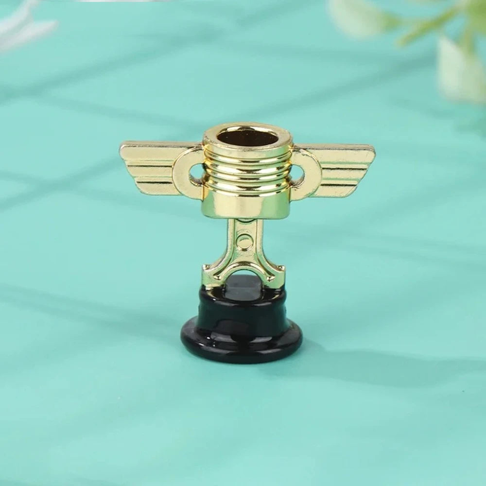 A small golden trophy cup with wings and a black base, displayed on a light blue surface.