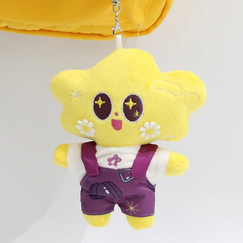 A yellow plush pendant doll of a character wearing purple overalls and a white shirt.