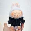 A Labubu doll wearing a black bear hoodie with headphones, held in a person's hand.