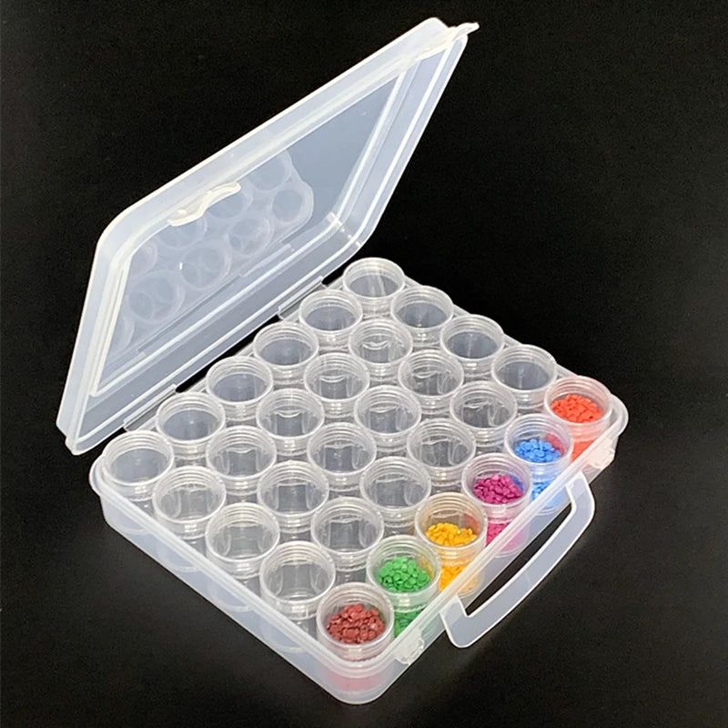 An open clear plastic storage box containing a grid of small round bottles filled with various colored liquid pigments.