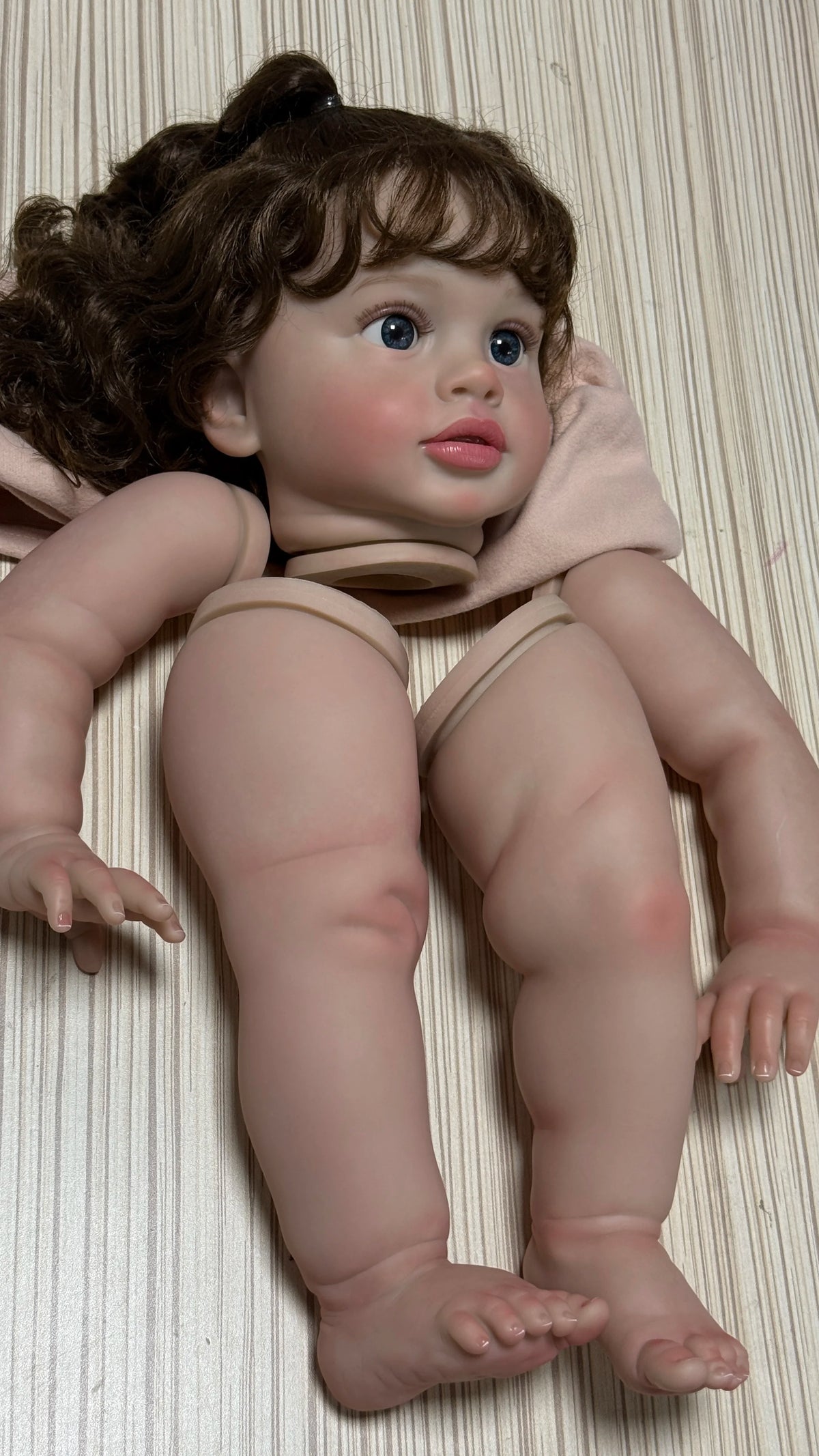 A lifelike reborn baby doll kit featuring painted vinyl parts, shown from the front.