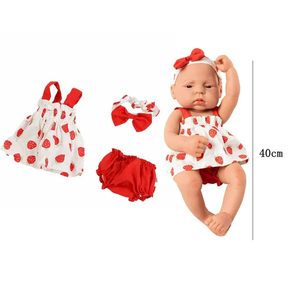 A baby doll wearing a red and white strawberry print jumpsuit with a matching bow, displayed next to the clothing.