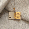 A gold and silver openable book necklace set with an engraved pendant featuring the text A mi increíble hijo (a).
