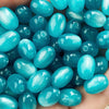 A handful of bright turquoise blue resin starry sky cat's eye beads for jewelry making