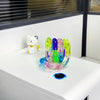 A collection of colorful crystal fidget twist ropes in various shades of green, purple, and yellow resting on a white surface