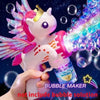 A hand holds a pink unicorn-themed bubble maker toy with colorful lights and sparkling wings.
