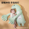 A soft green dinosaur plush toy designed for soothing babies, shown in a natural light setting.