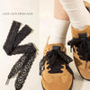 A close-up of brown suede shoes tied with black lace shoelaces on a person's foot.