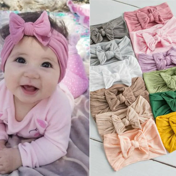 A collection of soft elastic bow headbands in various shades of pink, gray, and green for baby girls.