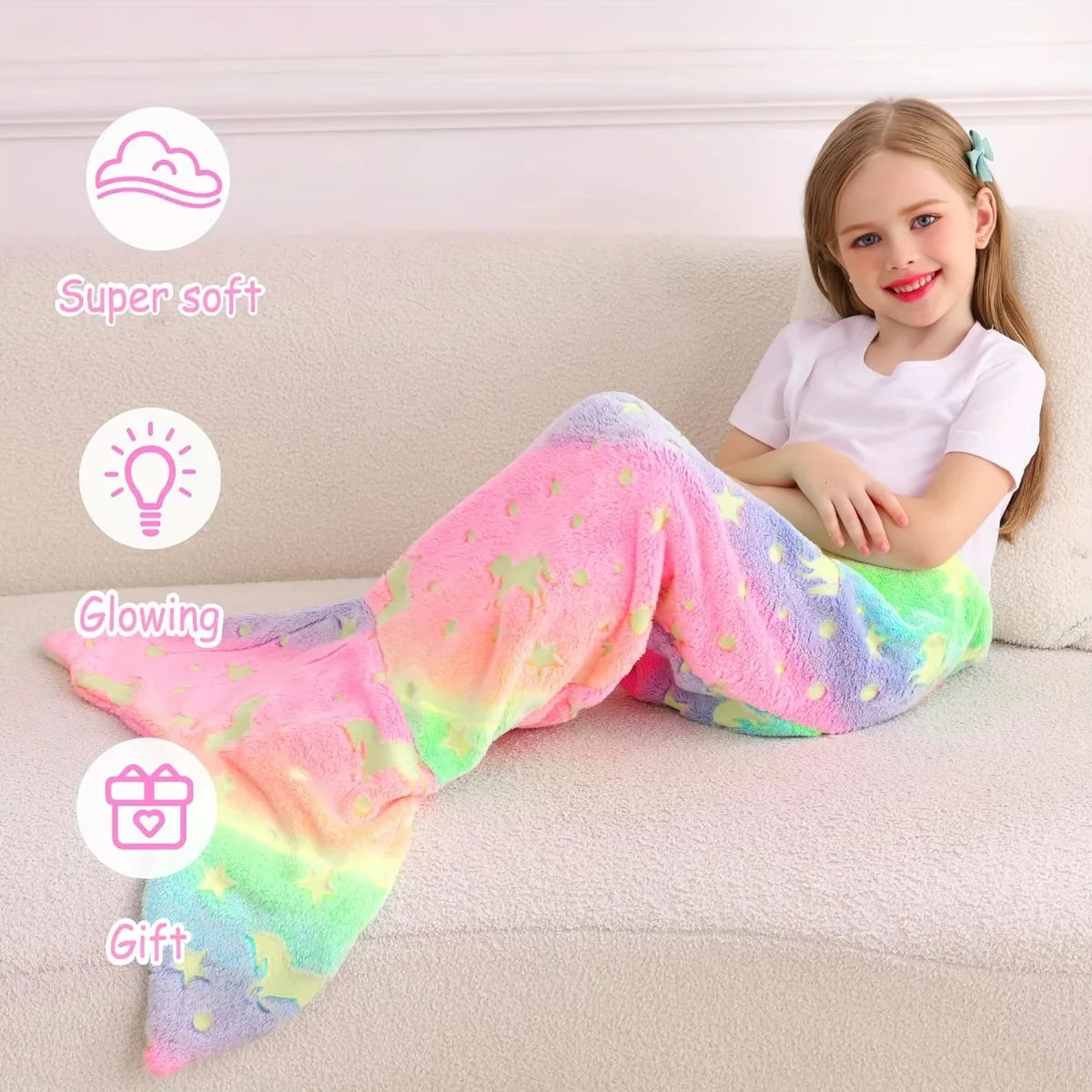 A young girl is sitting on a sofa wearing a bright, glow-in-the-dark mermaid tail blanket for kids.
