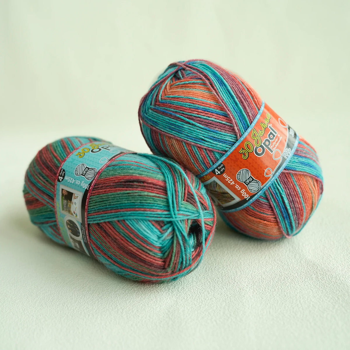 A ball of Opal 4-Ply Sock Yarn in a blend of teal, pink, and orange threads.