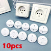 Ten white rotating socket safety covers for baby proofing displayed next to electrical outlets.