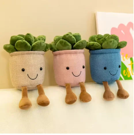 Three plush succulent toys in pastel pots with green leaves standing on a white surface.