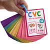A hand holds a stack of colorful CVC word building cards featuring pictures of a cat and a ram.