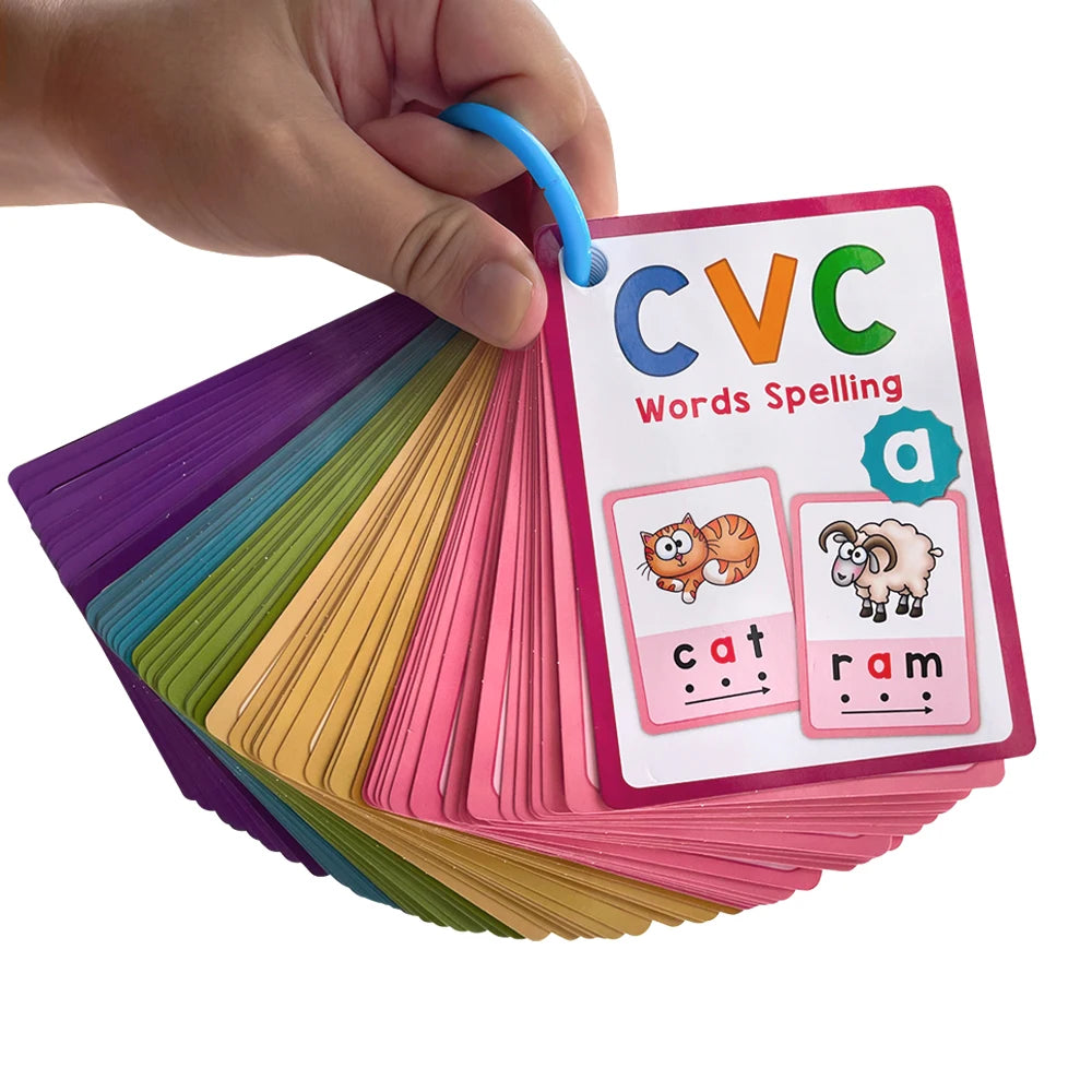 A hand holds a stack of colorful CVC word building cards featuring pictures of a cat and a ram.