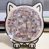 A circular jigsaw puzzle featuring many small, colorful cats arranged in a dense pattern on a wooden board.