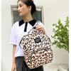 A woman is holding a leopard print cartoon print waterproof diaper bag in black and white against a light background.