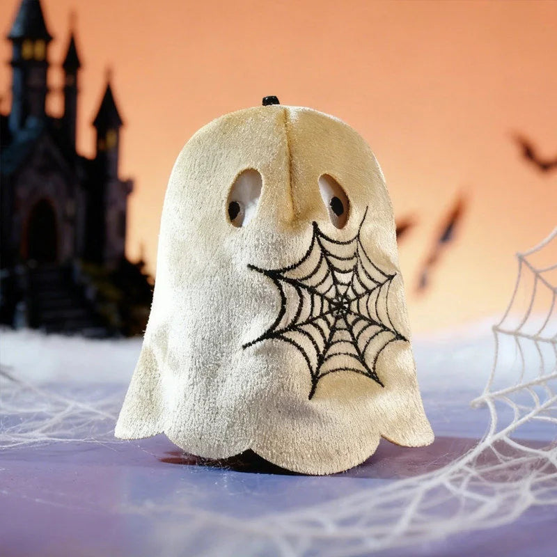 A white ghost-like figure with black spiderwebs is displayed on a surface against an orange background.