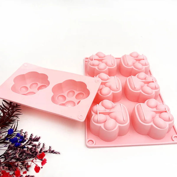 Moldes de silicona rosa en forma de pata de gato para jabón, vela y resina, sobre fondo blanco.