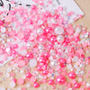 A pile of mixed resin rhinestone pearls in pink and iridescent colors for crafts and nail art.