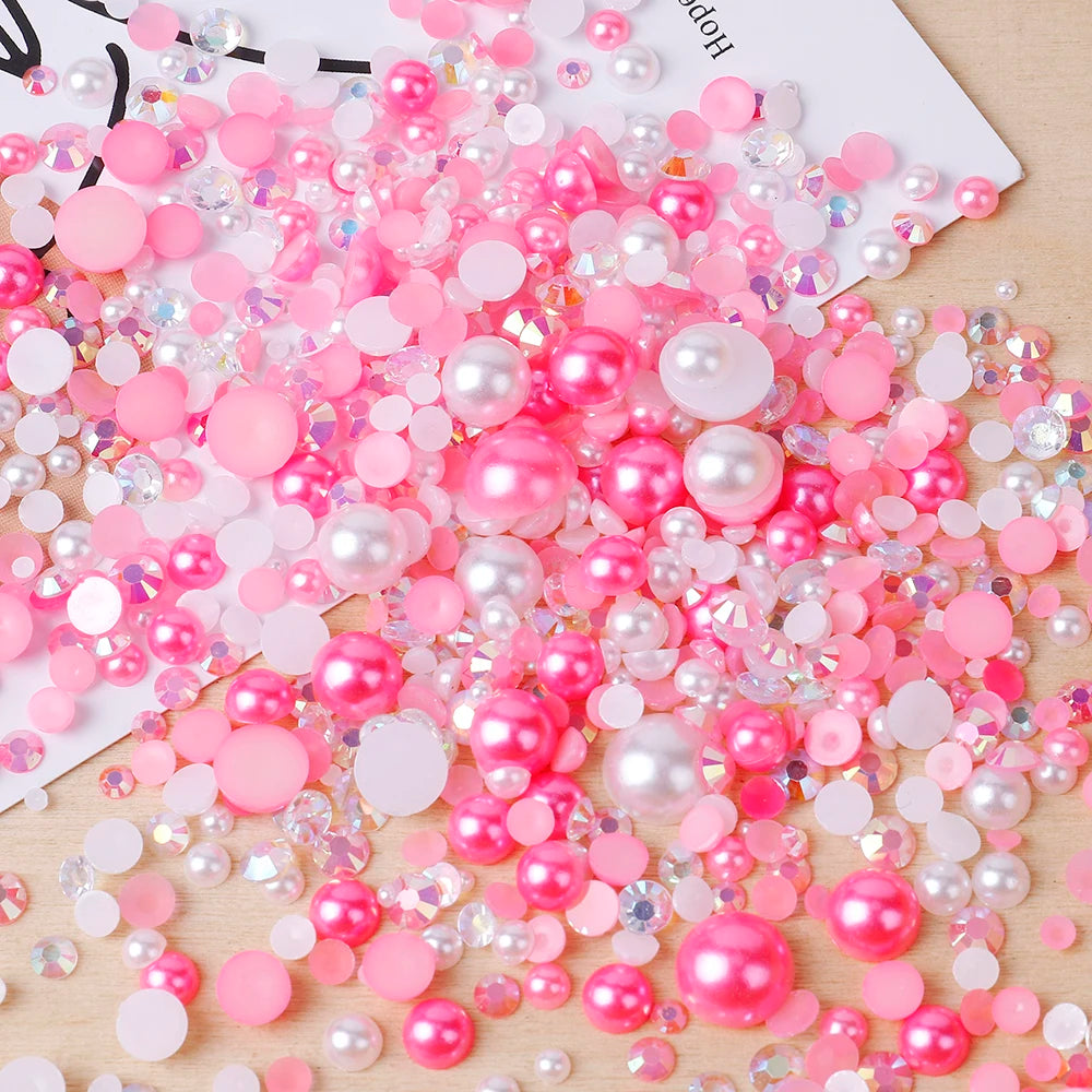 A pile of mixed resin rhinestone pearls in pink and iridescent colors for crafts and nail art.
