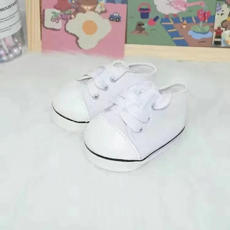 A pair of white canvas sneakers with white laces and black soles are displayed on a white surface.