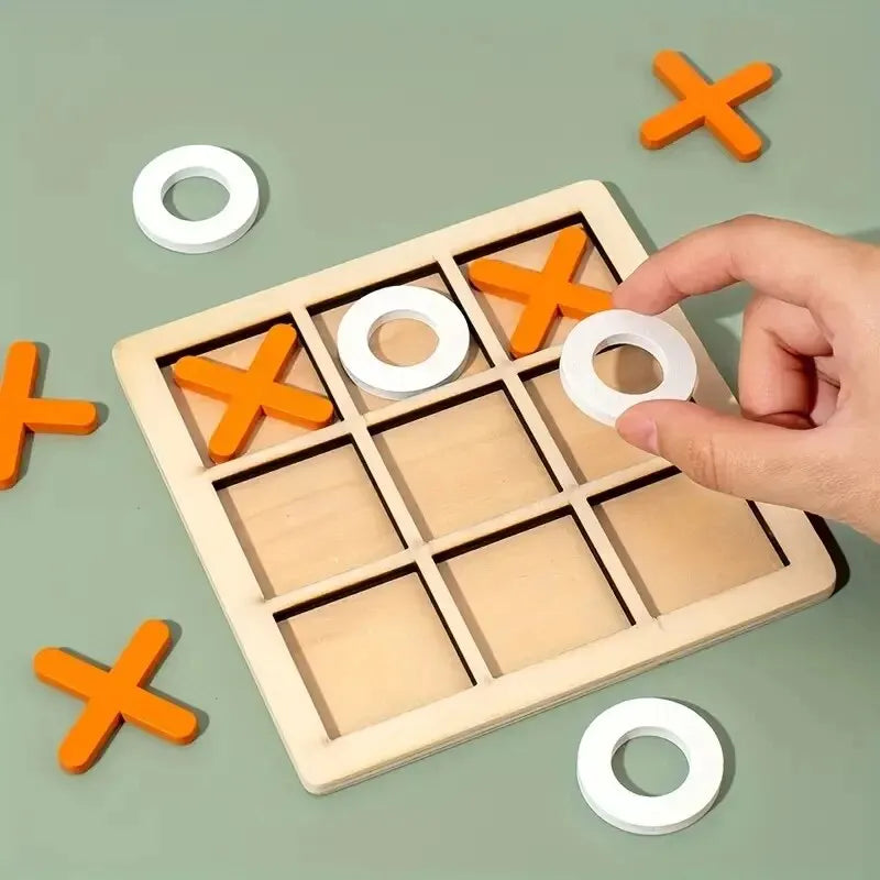 A wooden tic tac toe board game with orange and white pieces is being held by a hand on a green surface.