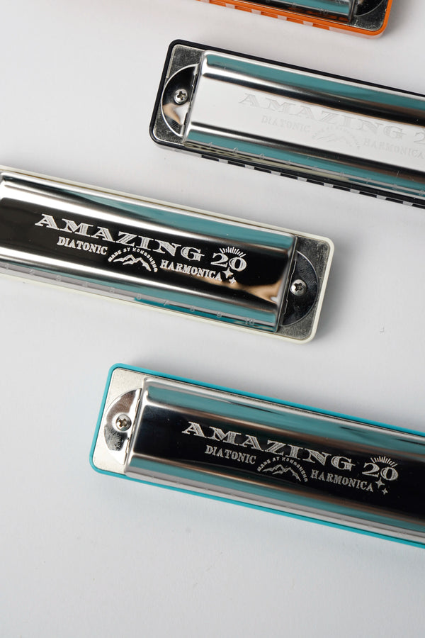 A silver-colored diatonic harmonica with black and white comb markings.