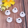 A set of five small white resin coffee cups for dollhouse kitchens resting on a wooden surface next to a yellow flower.