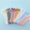 A collection of baby girl lace knee socks in various pastel colors and shades with bows arranged on a light blue background.
