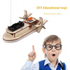 A wooden paddle boat kit with a motor and sails is shown next to a child demonstrating its use.
