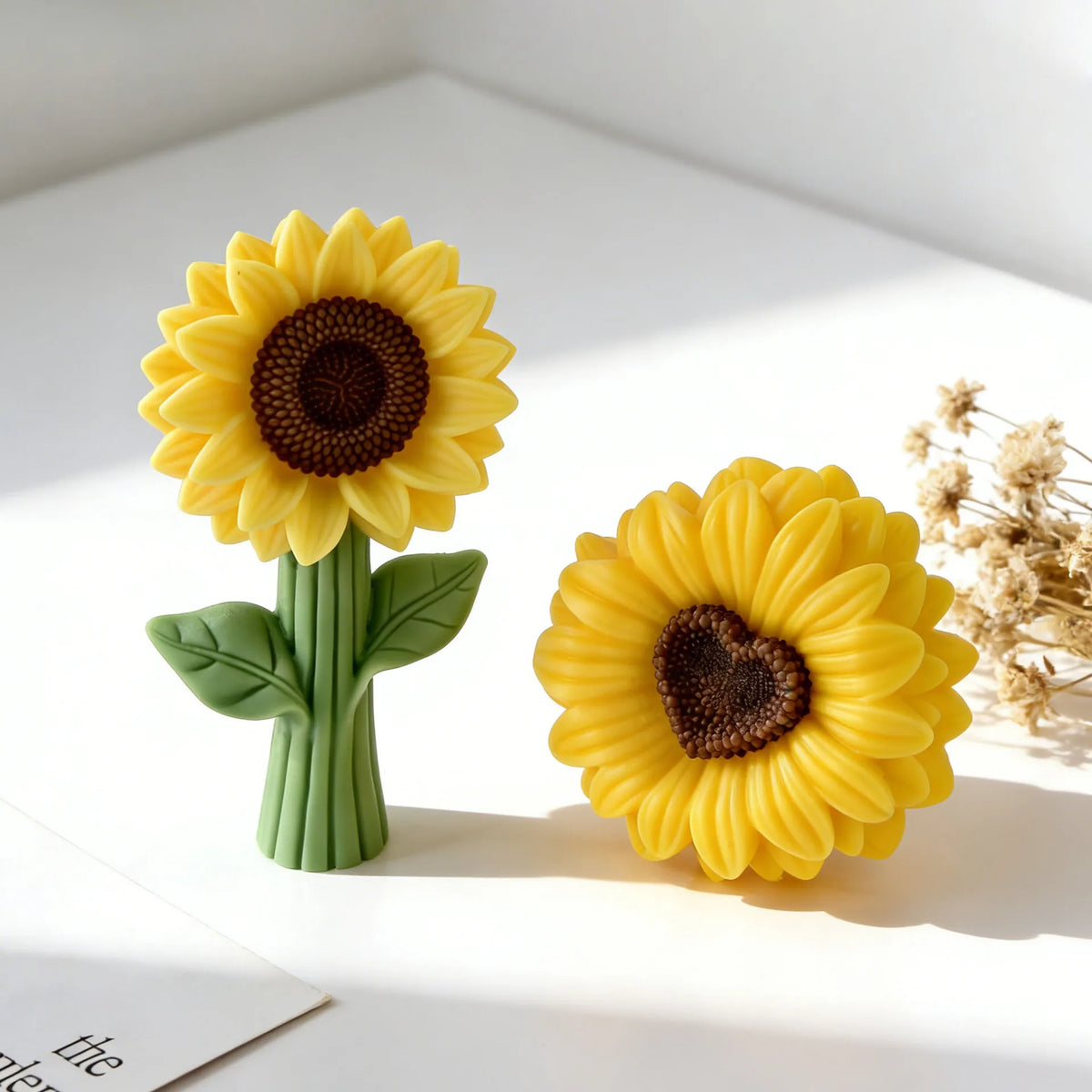 A bright yellow silicone sunflower mold with a dark center sits on a white surface.