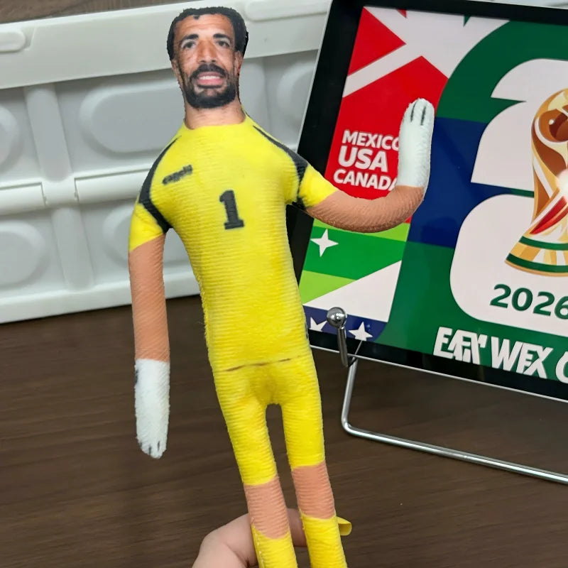 A yellow football star stuffed doll with flexible joints wearing a yellow jersey and white gloves.