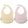 A pair of light beige and pink waterproof silicone baby bibs with adjustable necks.