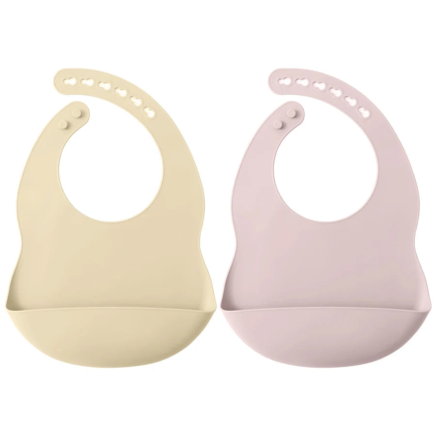A pair of light beige and pink waterproof silicone baby bibs with adjustable necks.