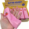 A hand holds a pink strawberry squishy toy inside its original packaging box.