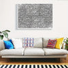 A framed black and white abstract line art jigsaw puzzle hanging on a white wall above a gray sofa.