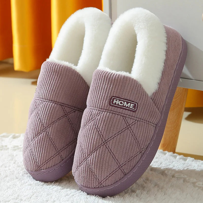 Pair of mauve knitted slippers with white faux fur lining resting on a white surface.