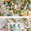 A collection of colorful butterfly stickers, including green, blue, and yellow varieties, arranged on aged paper and natural 