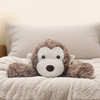 A fluffy brown monkey plush toy resting on a light beige blanket.