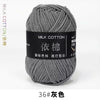 A ball of gray milk cotton yarn with a black label and Chinese text for knitting and crochet