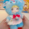 A fluffy blue anime-style doll with pink accents and a bow is held in a person's hands.