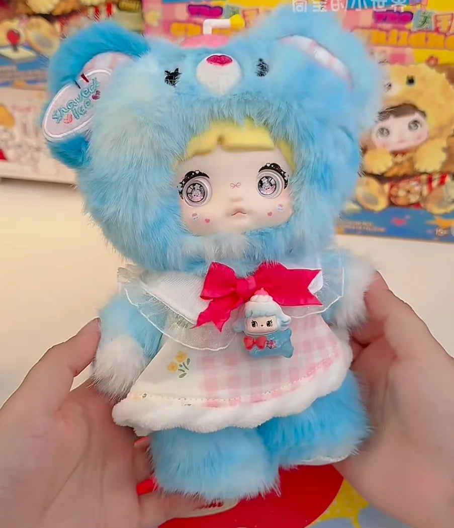 A fluffy blue anime-style doll with pink accents and a bow is held in a person's hands.