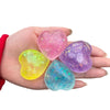 Hand holding four glowing heart-shaped squishy toys in pink, purple, yellow, and blue hues