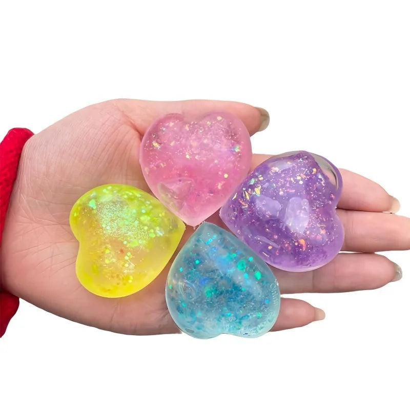 Hand holding four glowing heart-shaped squishy toys in pink, purple, yellow, and blue hues