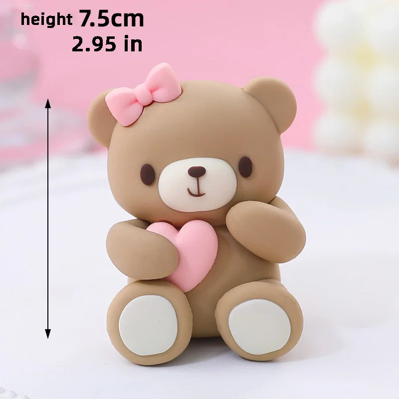 A cute, light brown bear-shaped cake topper with pink accents and a bow, shown against a white background.