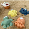 A set of plastic sea creatures and a small orange container are placed on sand.
