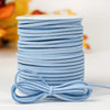 A stack of light blue velvet faux suede braided ribbon rolls for crafting and gift wrapping.
